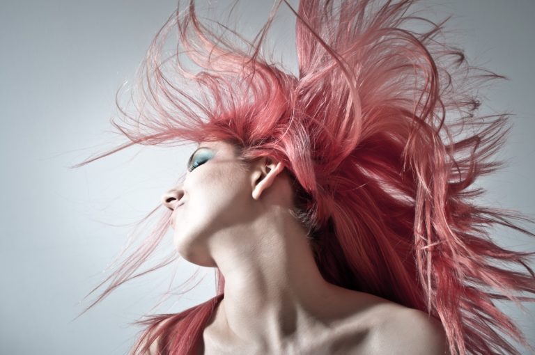 Frau, die ihr rosa Haar zurückwirft (Quelle: George Bohunicky / Unsplash)