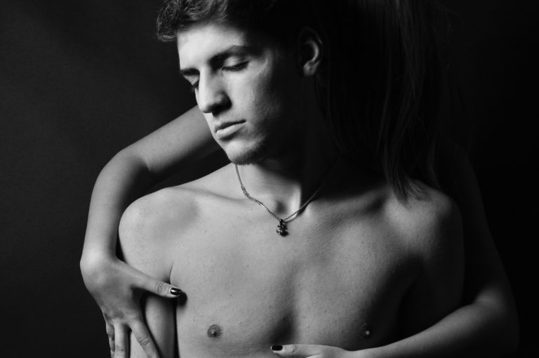 Mann mit nacktem Oberkörper wird von hinten umarmt (Photo by Emiliano Vittoriosi on Unsplash)